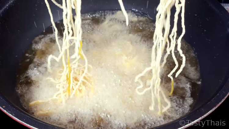 Frying the crispy Khao Soi Noodles to go on top