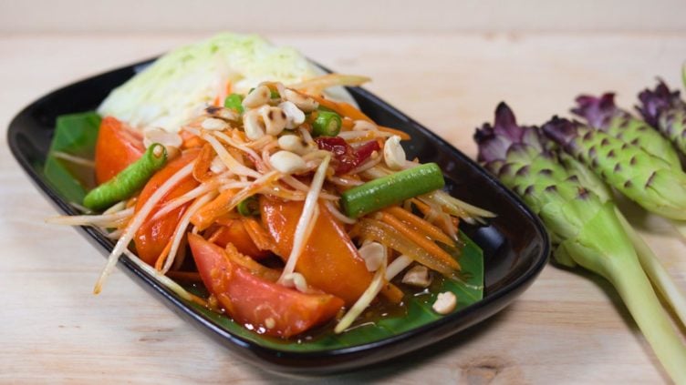 Photo of a plate of som tam thai papaya salad with shredded papaya and tomatoes