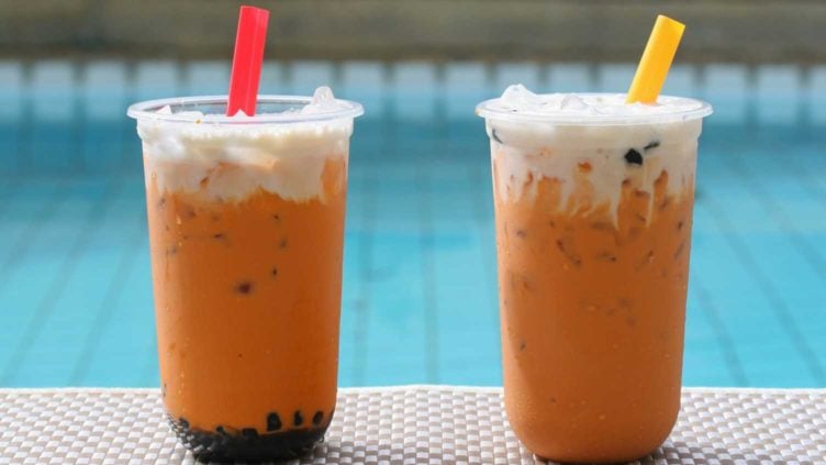 photo of two cups of Thai Iced Milk Tea and Boba Milk Tea by a swimming pool