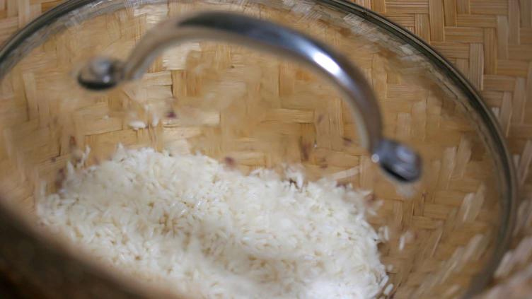 Photo of sticky rice in a bamboo steamer covered with a lid to steam properly