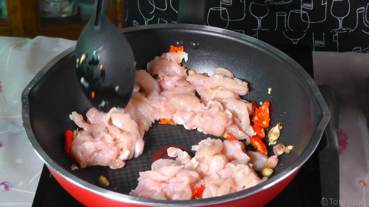 photo of sliced chicken added to teh cooking garlic and jinda chili