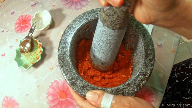 photo showing pounding and mixing of ingredients to red curry paste to make panang curry paste