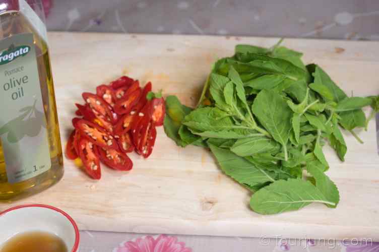 photo of Thai holy basil with sliced chili spur and cooking oil