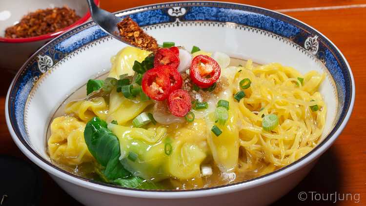 photo of adding condiments to finish wonton noodle soup with spice