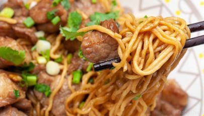 beautiful photo of stir fried pork with egg noodles dish served and close up