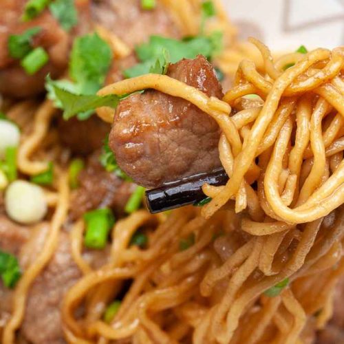 beautiful photo of stir fried pork with egg noodles dish served and close up