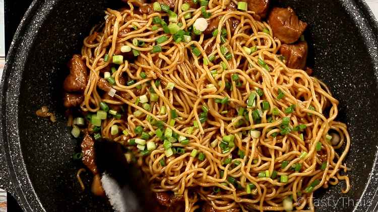 photo of end of stir frying the pork noodles and green onions added