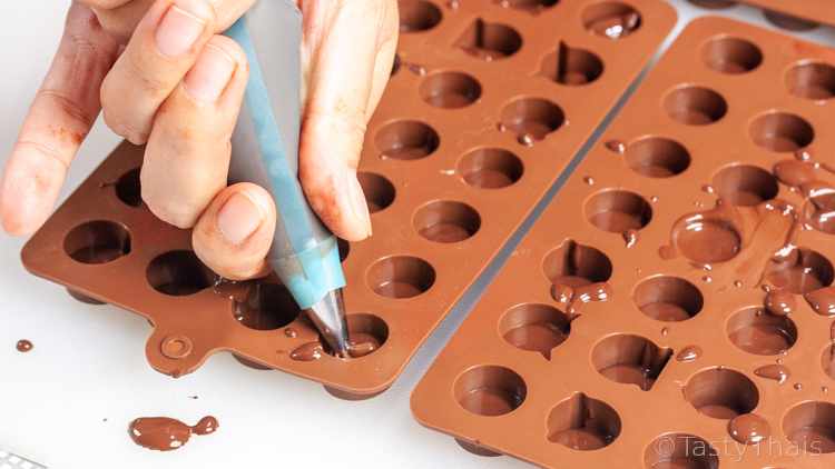Adding the base layer of chocolate to the mold which makes the emoji face