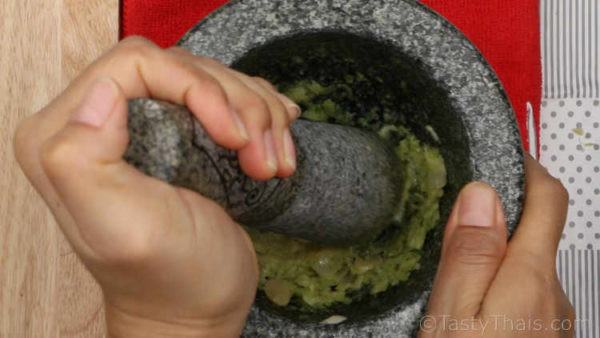 Pounding the seafood dipping sauce ingredients in a mortar and pestle